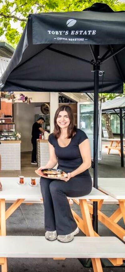 Two Cafe Cultura workers standing outside of the cafe, holding plates of food.