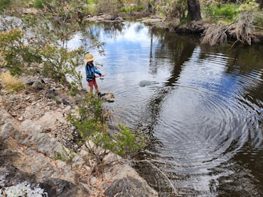 Person fishing a waterhole Person fishing a waterhole