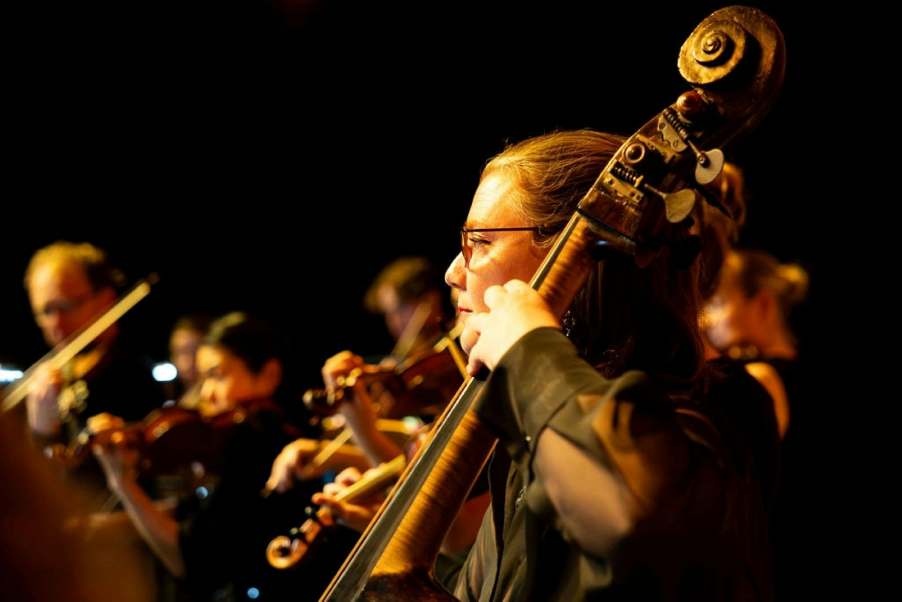 Woman playing cello within a larger orchestra