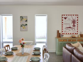 Dining table set for six beside leather sofa and artwork