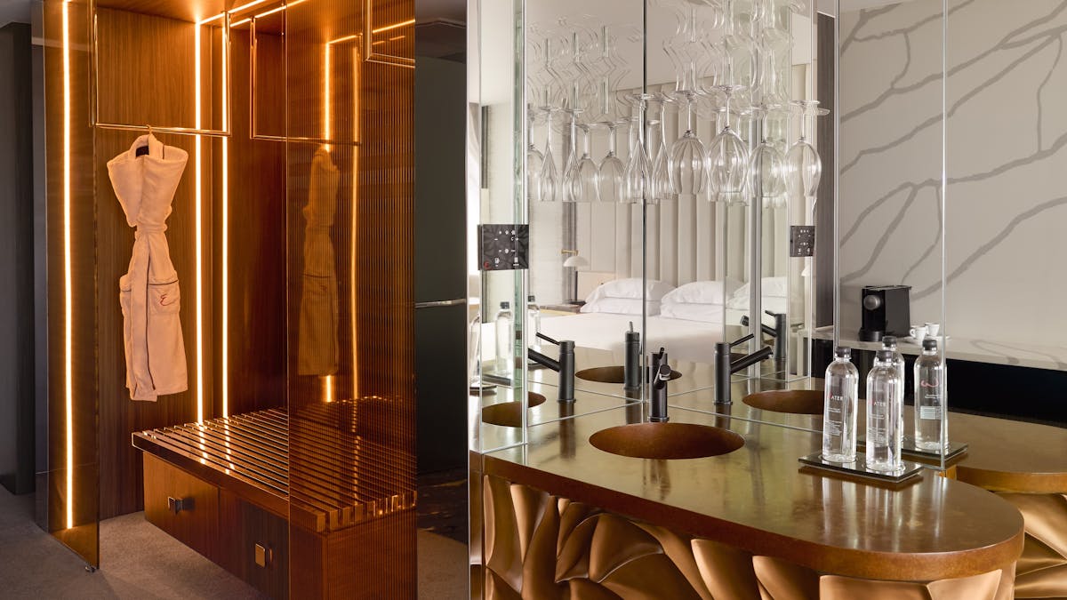 Illuminated dressing area and mirrored bar with hanging glassware in a luxury suite