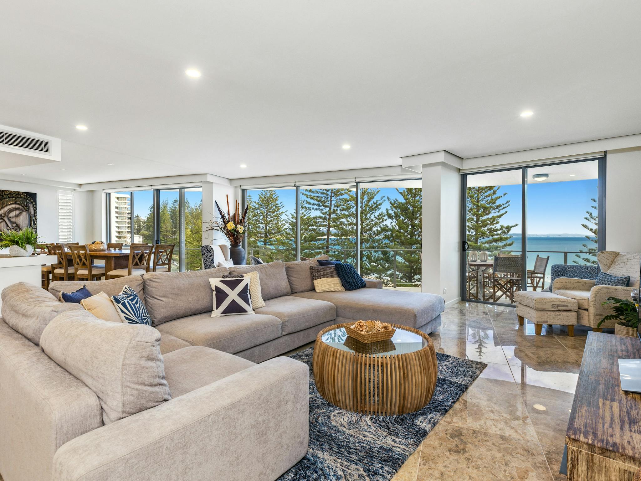 Cozy lounge with warm tones, grey corner sofa, marble tiles, and beautiful ocean views Cozy lounge with warm tones, grey corner sofa, marble tiles, and beautiful ocean views