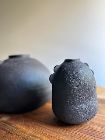 Two round dark coloured vases