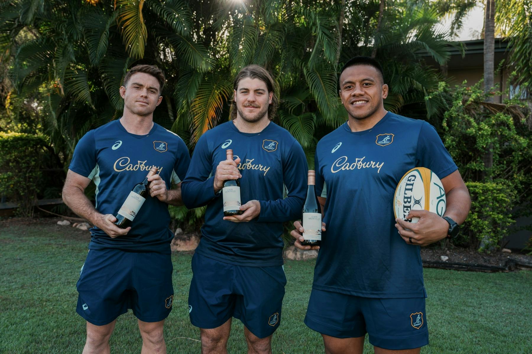 Three Wallabies players holding bottles of Cape Mentelle Wine and a rugby ball
