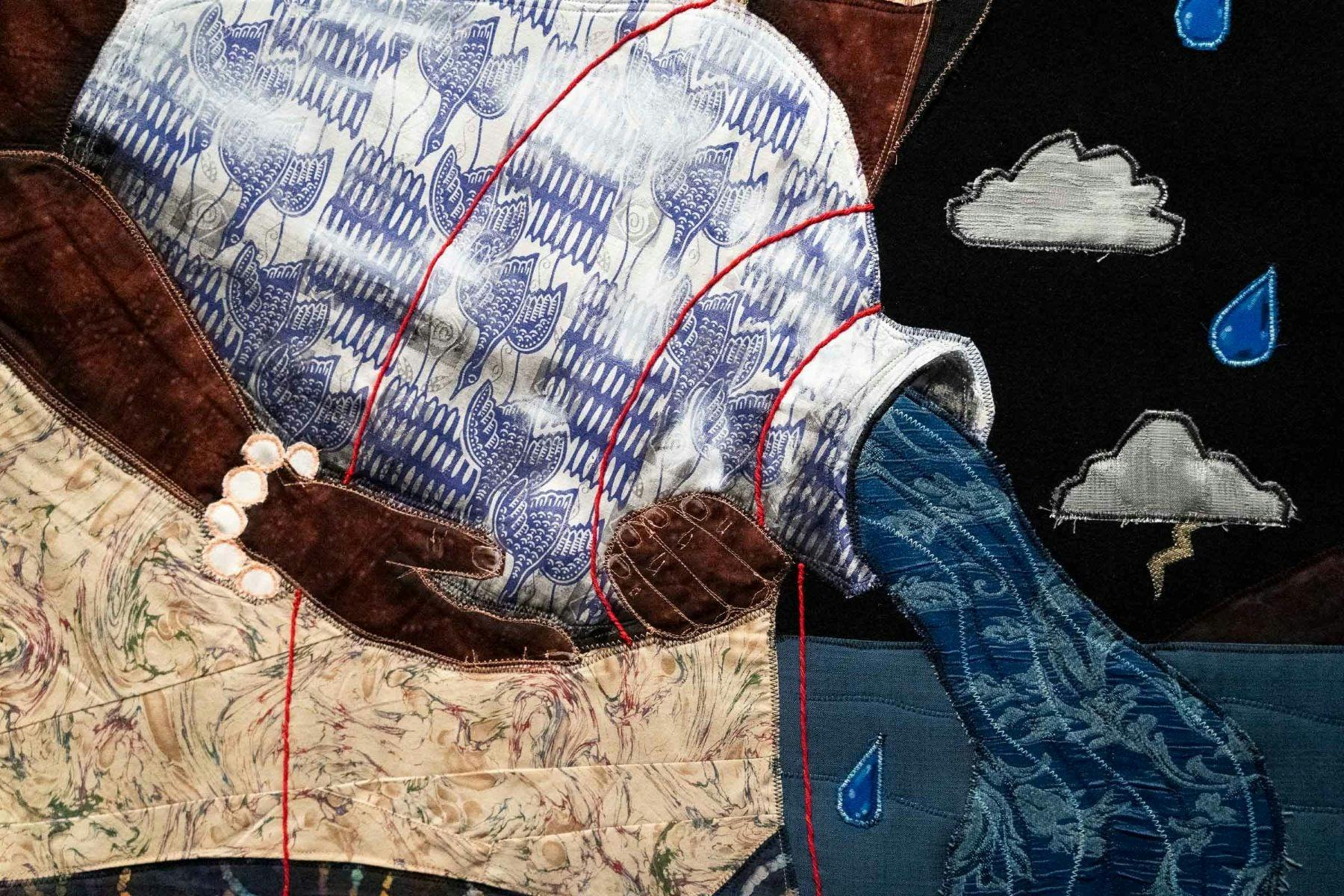 Close up of quilted textile artwork, showing a woman holding a water vessel