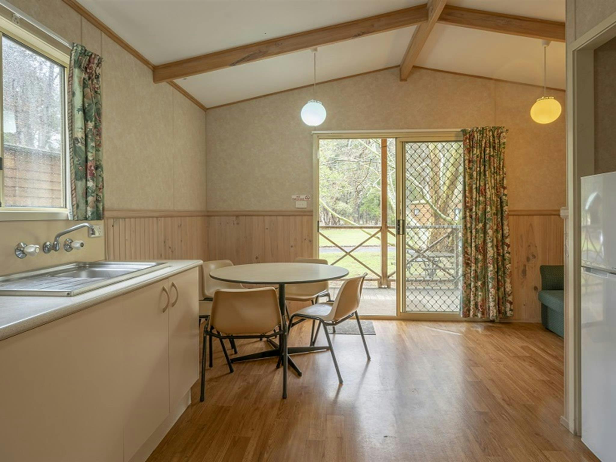 Inside one of the Wombeyan Caves cabins, showing the kitchen, dining table and open sliding glass