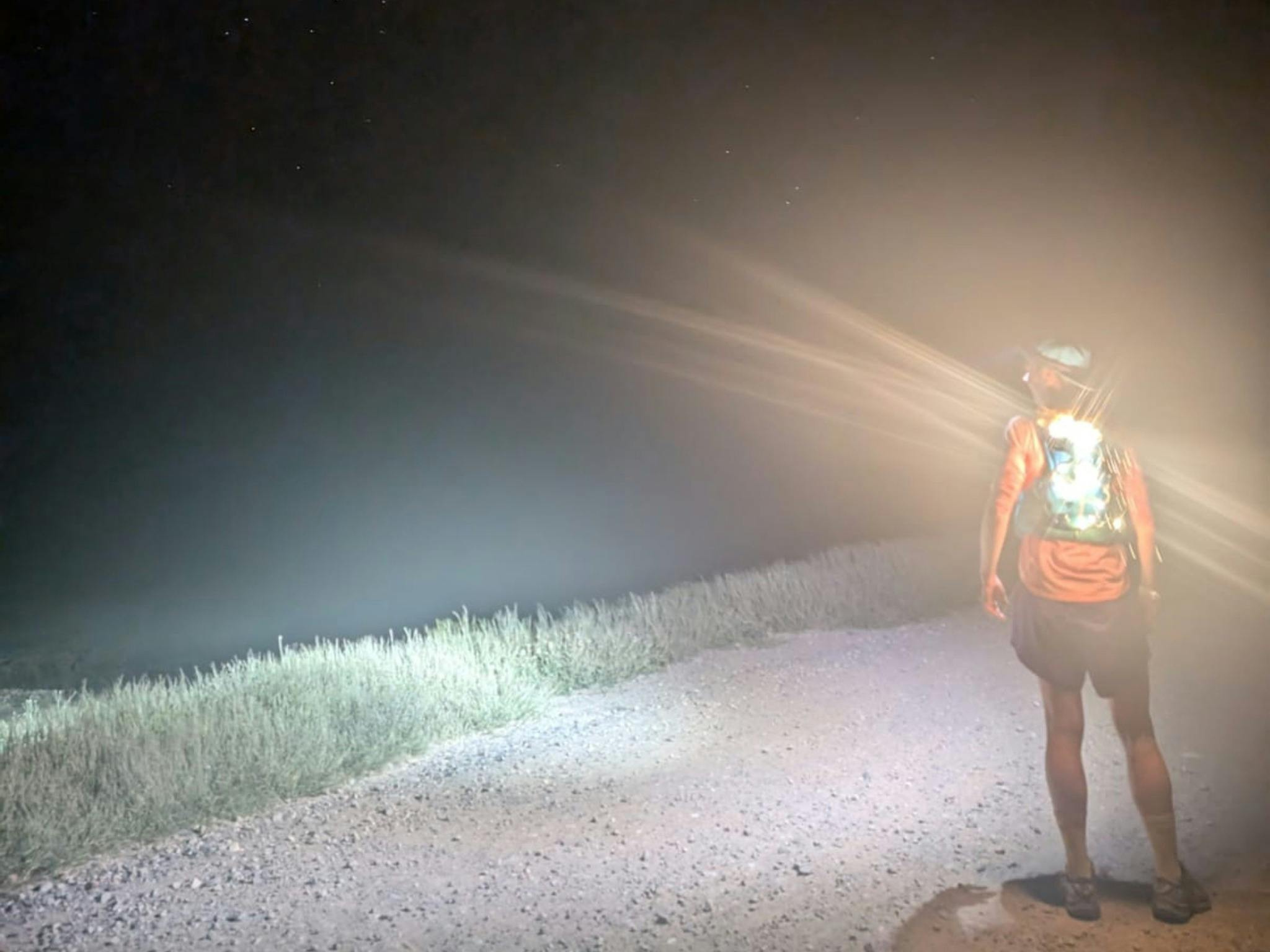 Person with fiarylight on backpack - surrounded by pitch blackness in the night.
