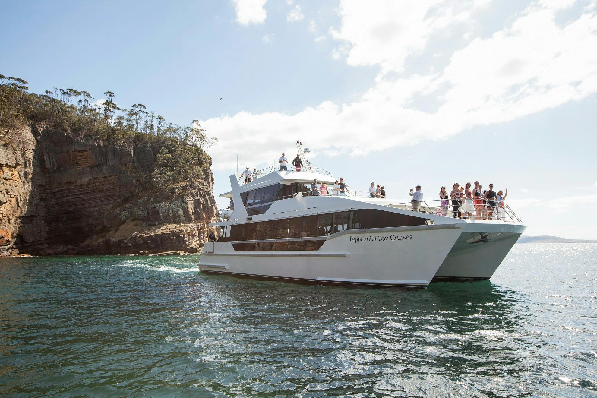 A cruising catamaran with guests on the viewing decks