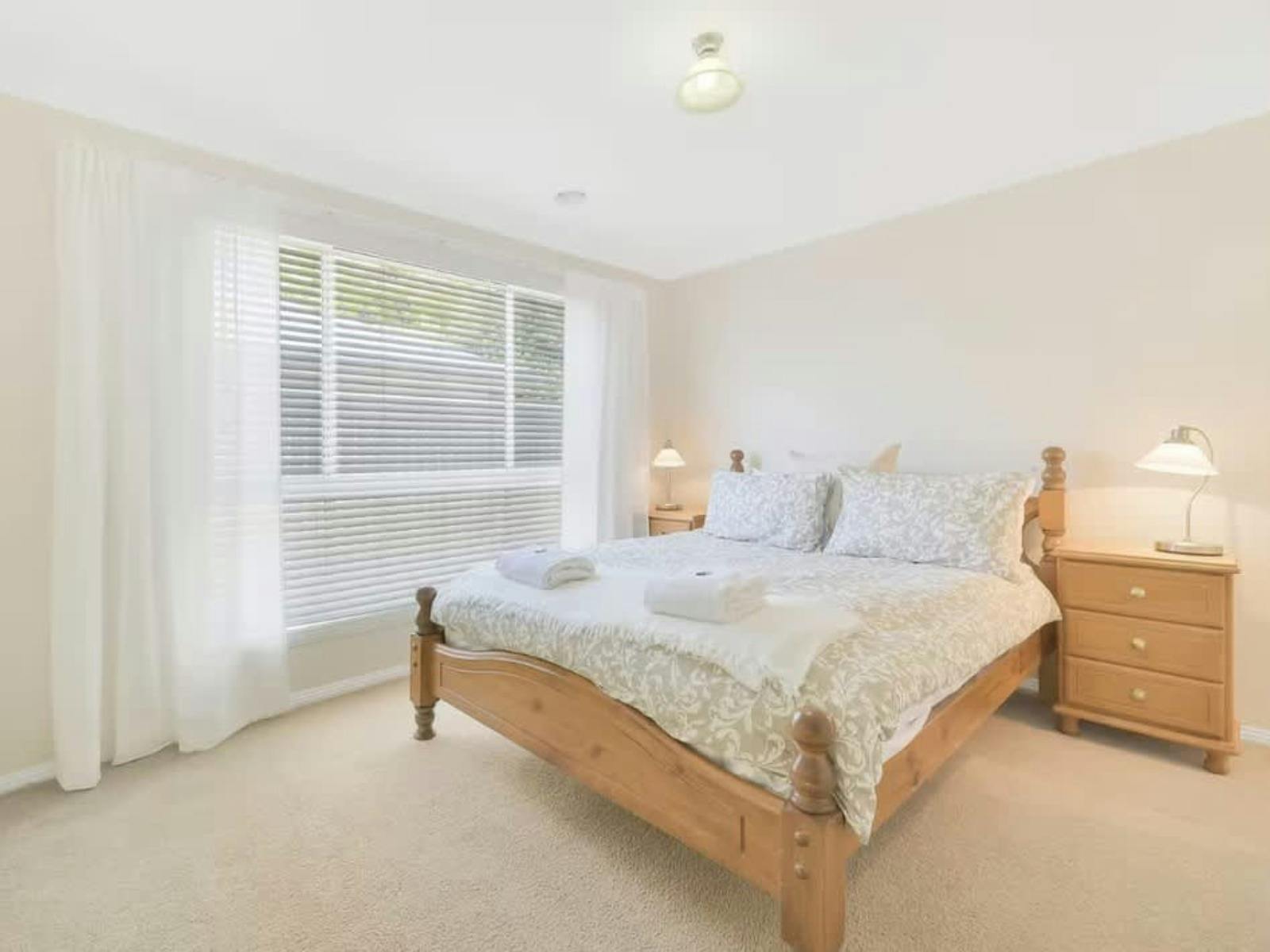 Bedroom with wooden furniture, curtain and blinds