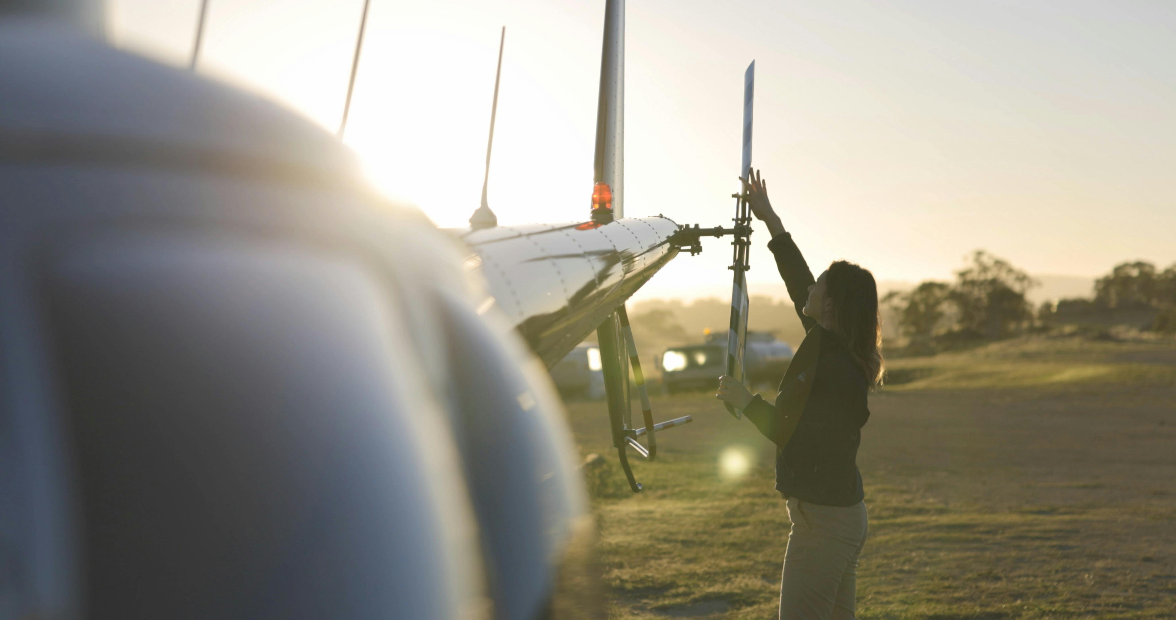 Pilot (Meg) performing pre-flight inspections of the helicopter.