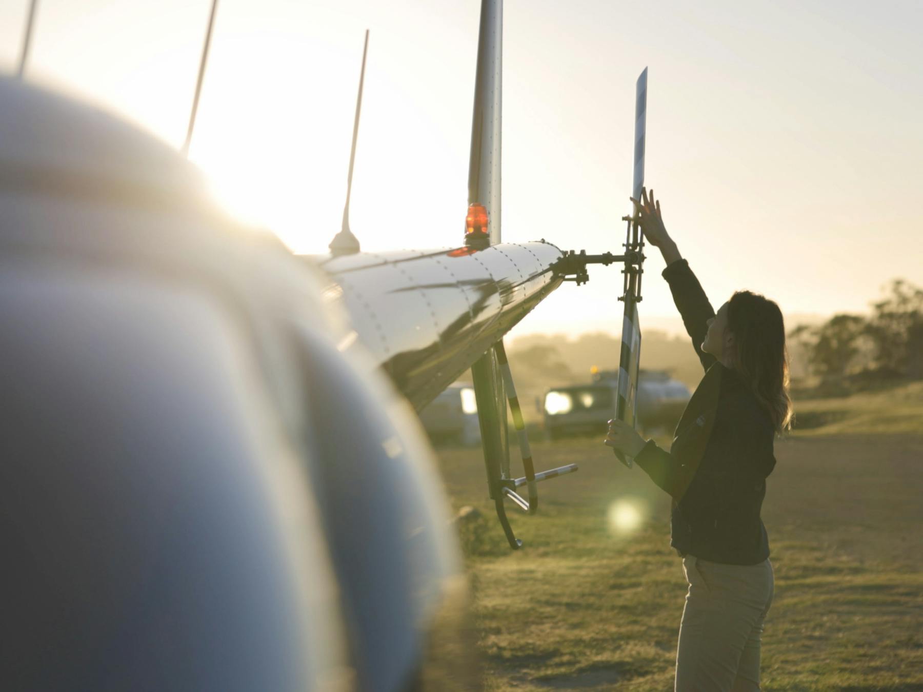 Pilot (Meg) performing pre-flight inspections of the helicopter.