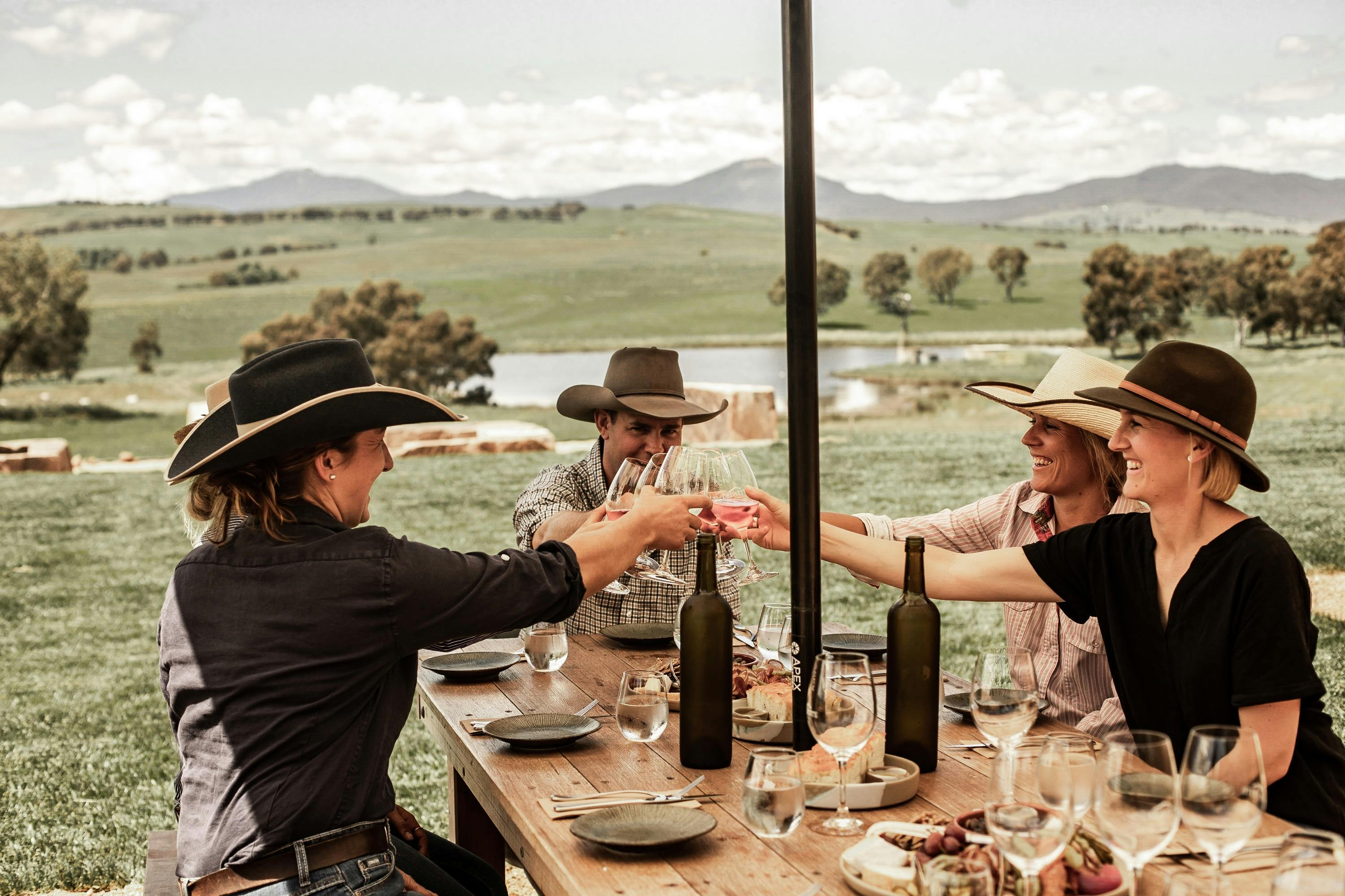 four people sitting at a table cheering their glasses together