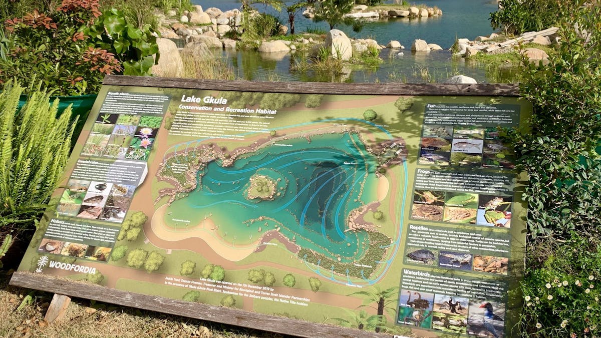 Info board giving map and flora and fauna legend for Lake Gkula. Lake in background.