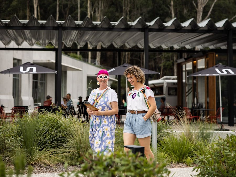 Two woman chatting as they walk leave Bundanon, with Ramox Cafe and the Art Museum in the background
