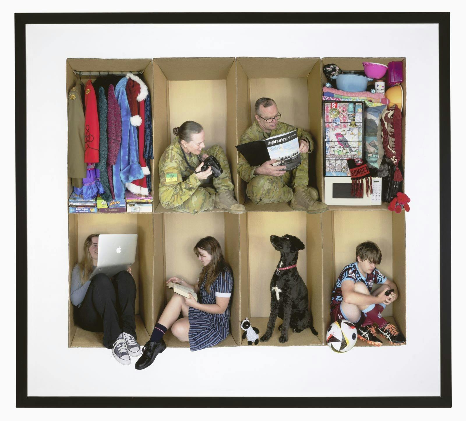 moving boxes with objects in them and family members sitting in some of the boxes