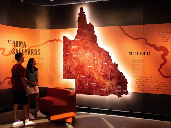 A couple look at a large map of Queensland showing stock routes A couple look at a large map of Queensland showing stock routes