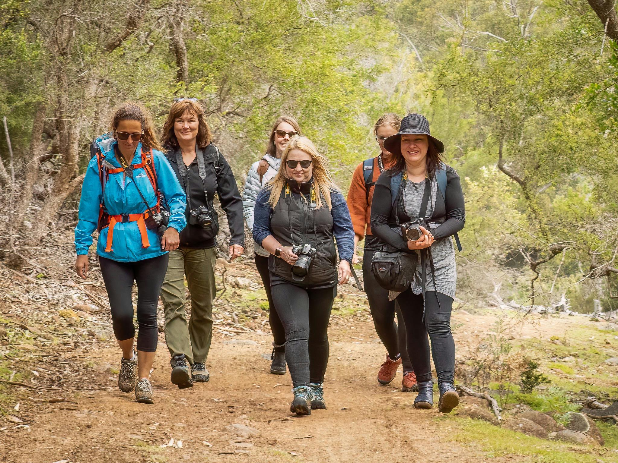 a small group of female photographers wandering along a nature trail with their cameras