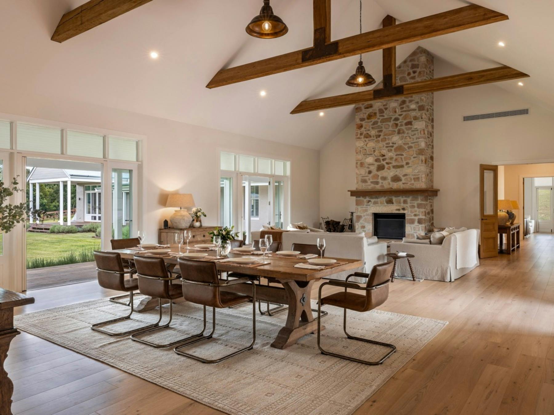 Spacious living and dining area with stone fireplace and timber beams at Stonehaven Estate