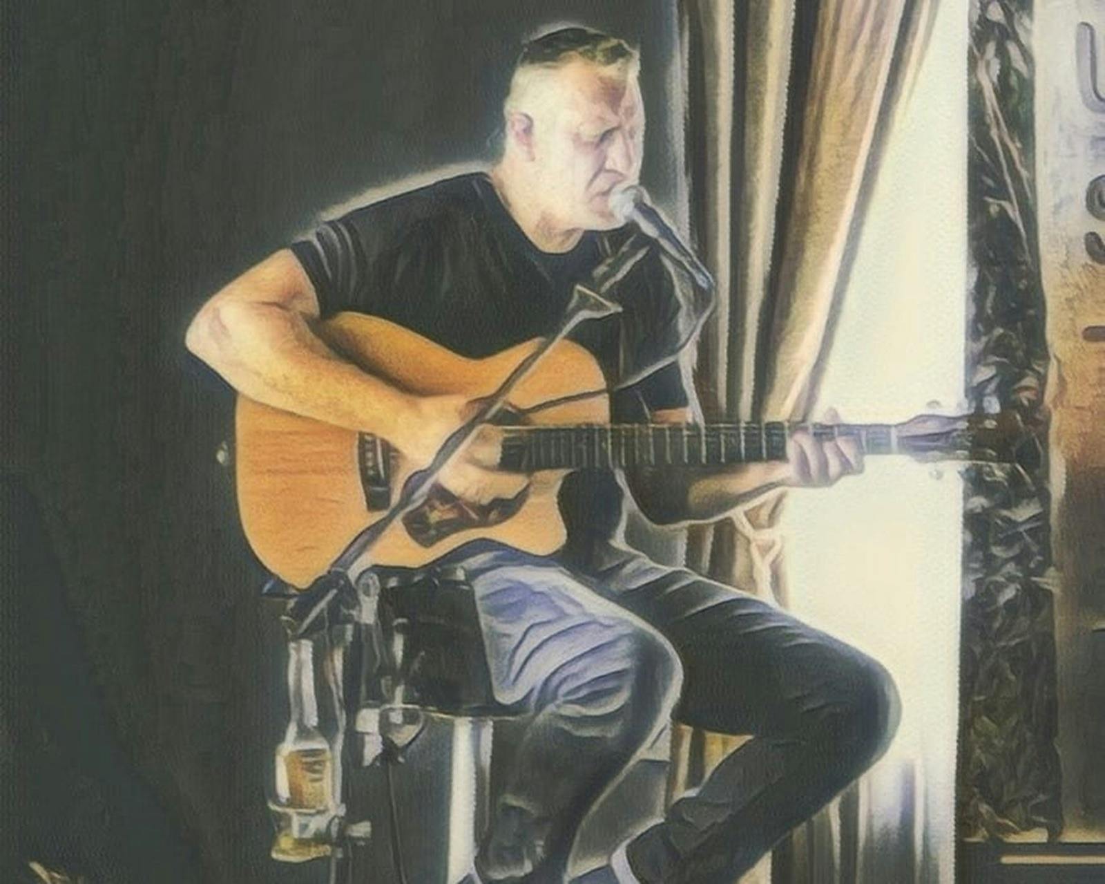 a man sitting on a stool playing  a guitar