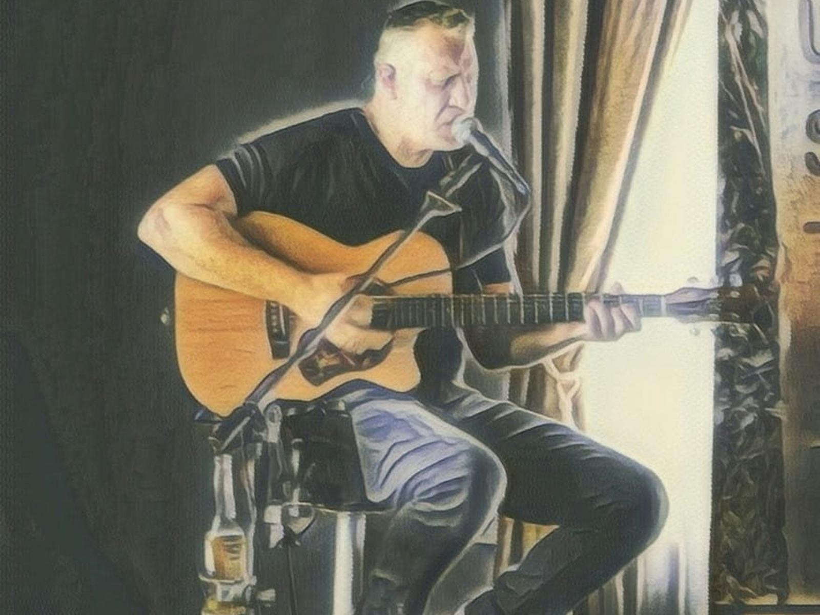 a man sitting on a stool playing a guitar