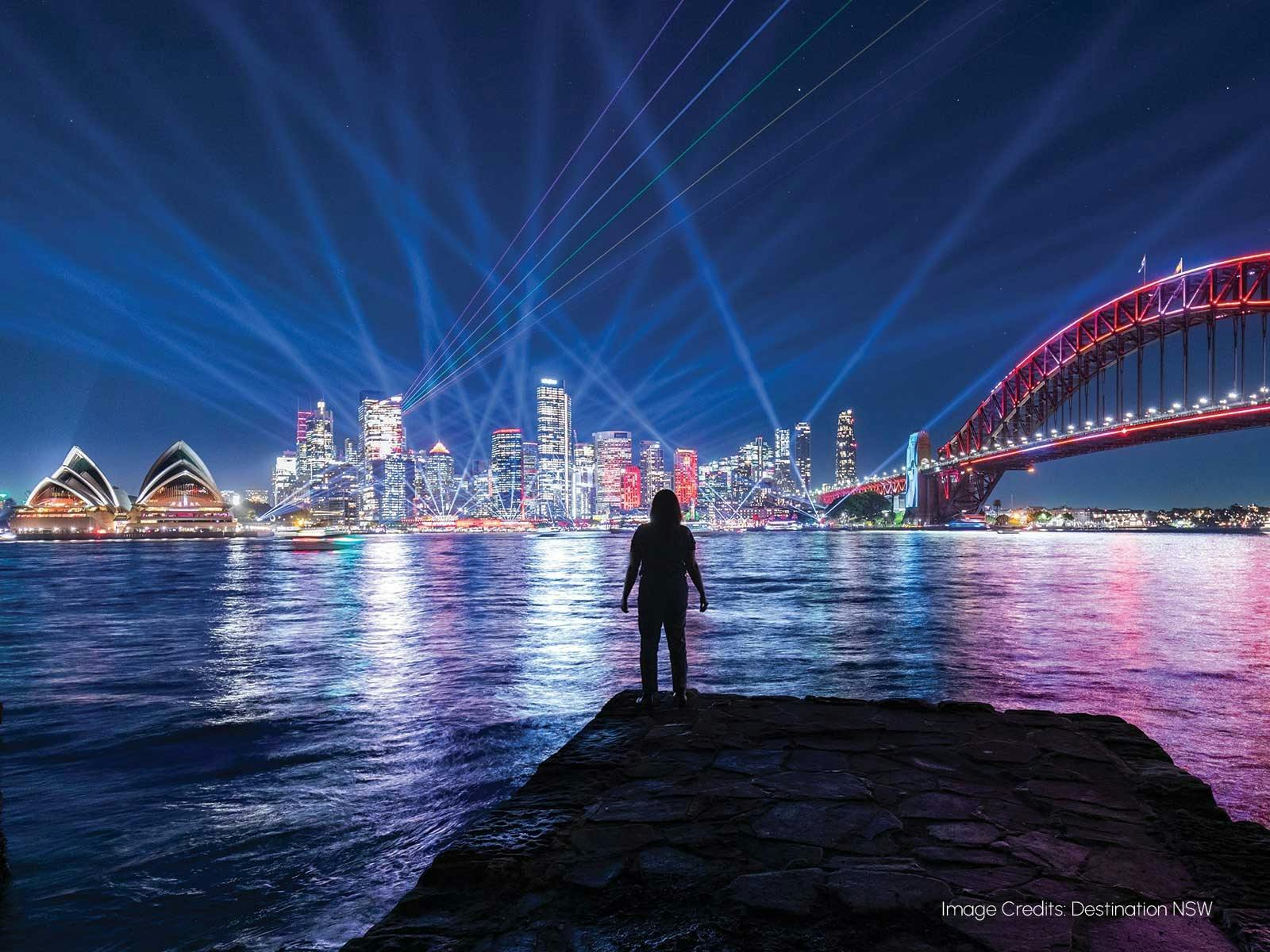 ビビッド・シドニーの広角夜景。前景に人物のシルエットが映っています。