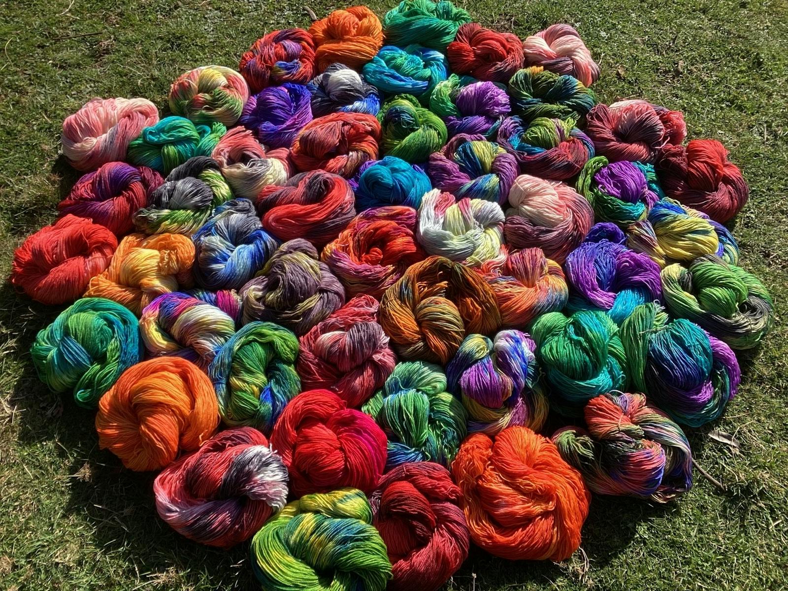 Bright coloured spools of yarn placed on grass
