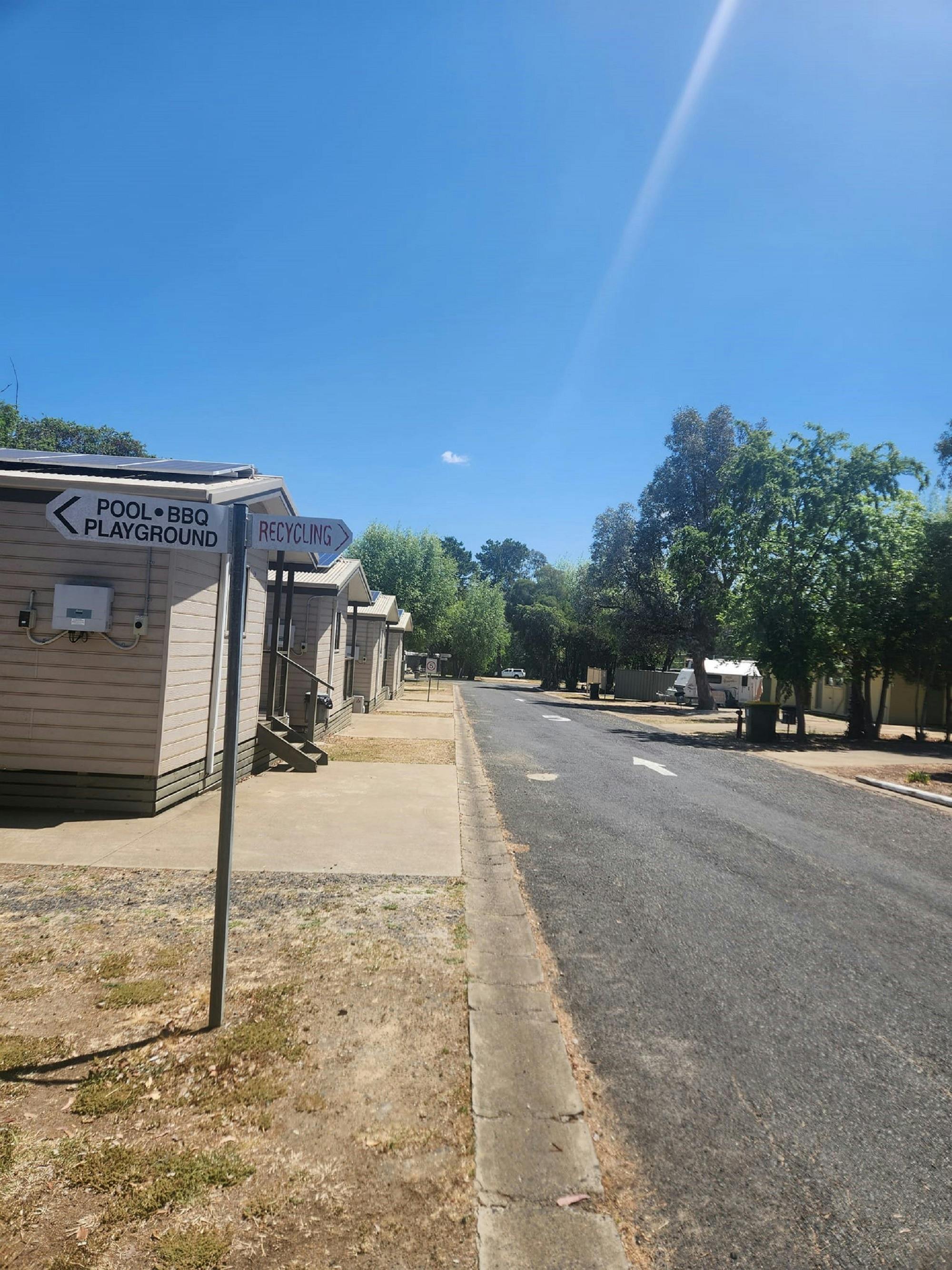 Row of Cabins on left with road passing in front of cabins and trees in background.