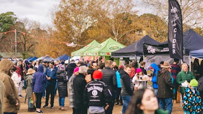 A crowd in front of several cider stalls perusing the offerings.