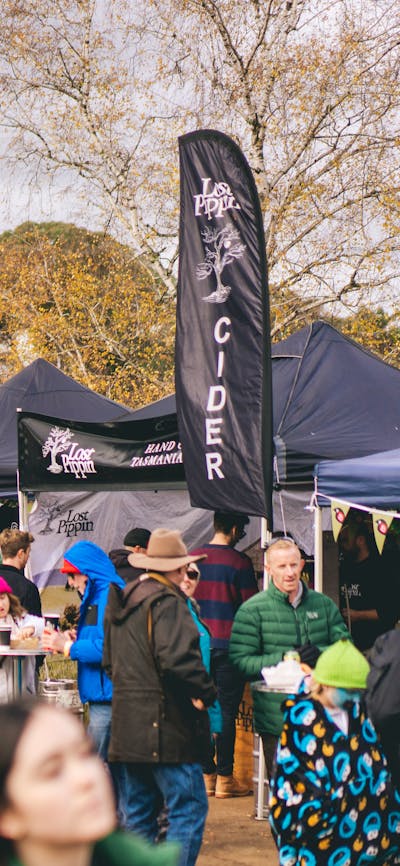A crowd in front of several cider stalls perusing the offerings.