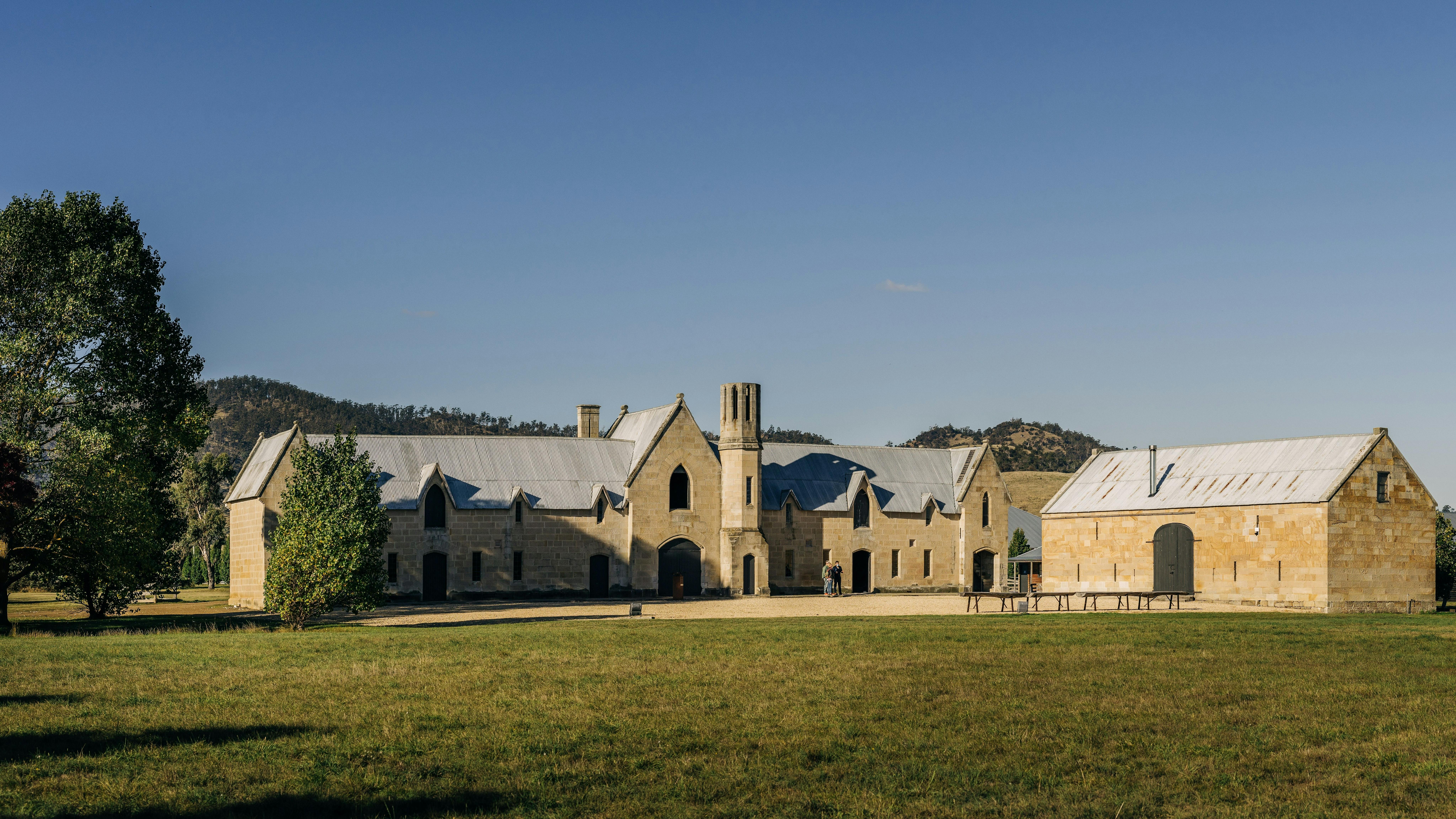 Grand sandstone buildings surrounded by grass tress and hills