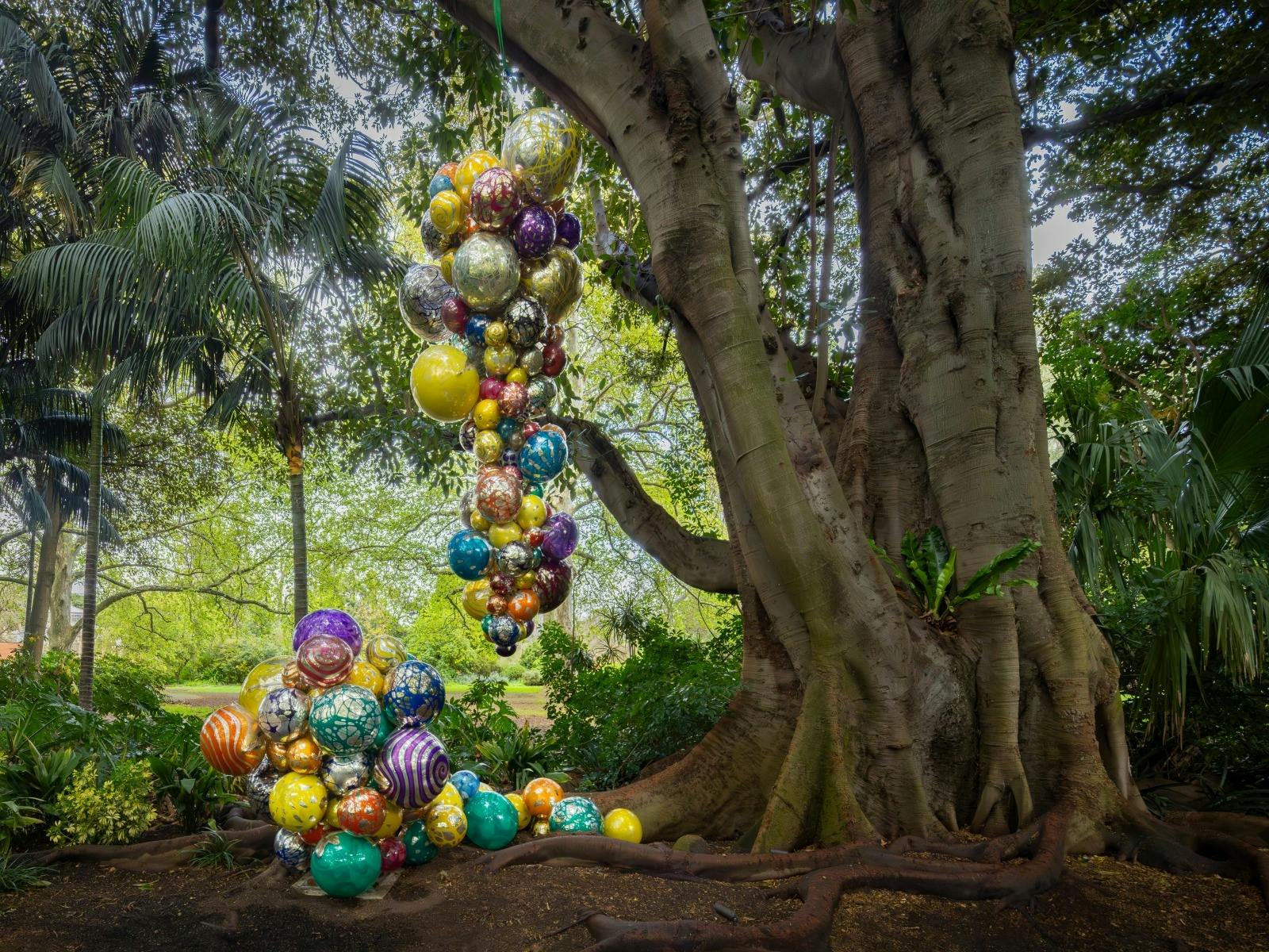 Large colourful sculpture hanging from trees
