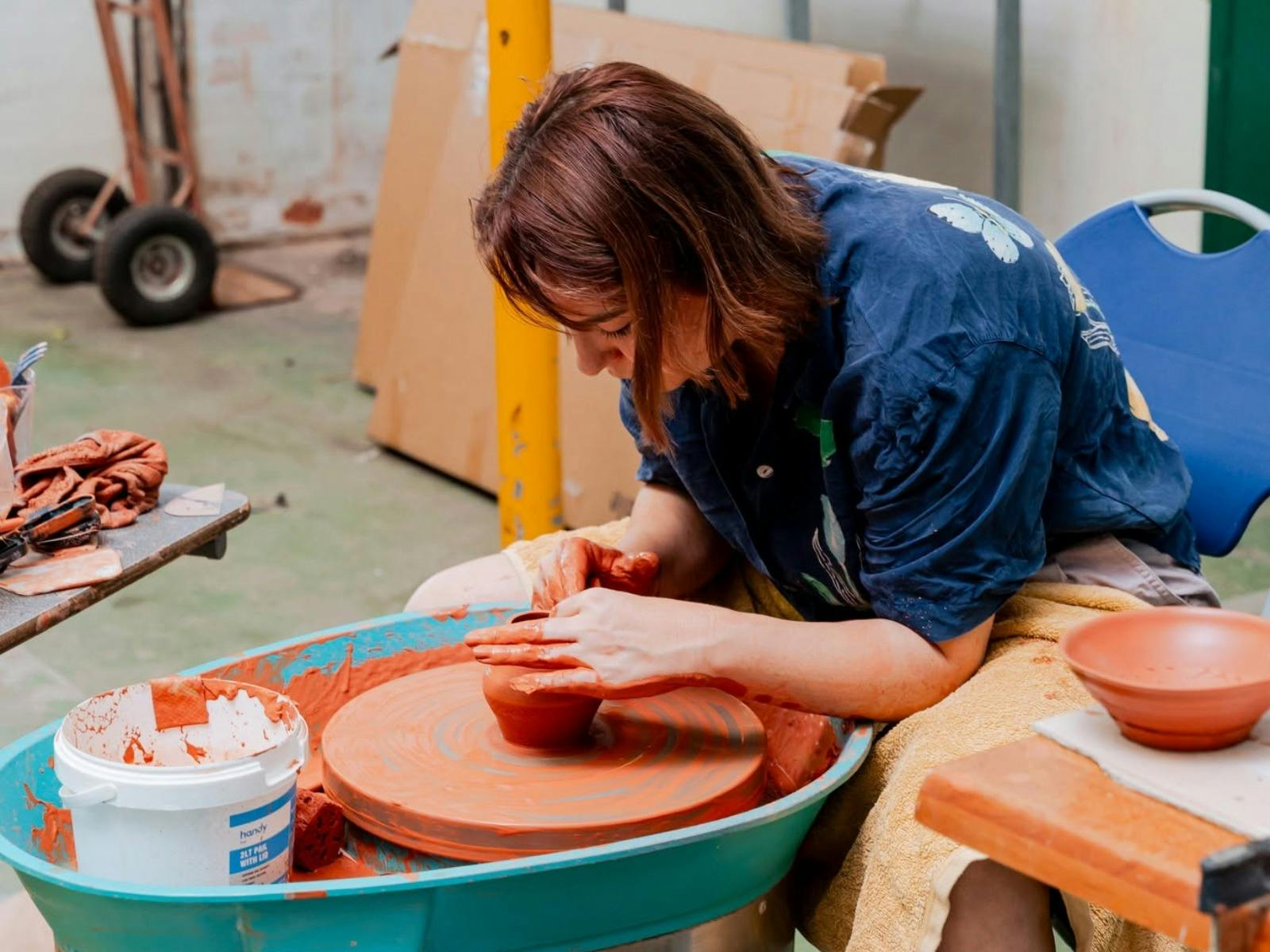 A women throwing pottery on a ceramics wheel
