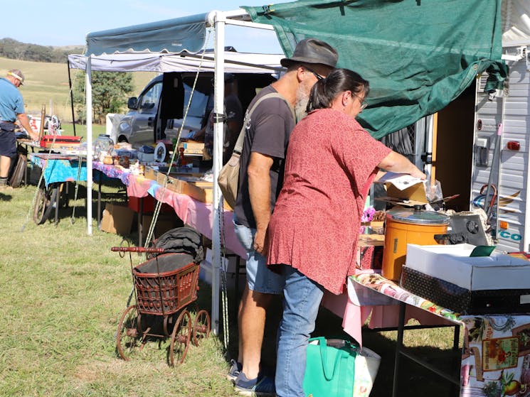 A woman in foreground and man, both in profile, viewing items on a stall table