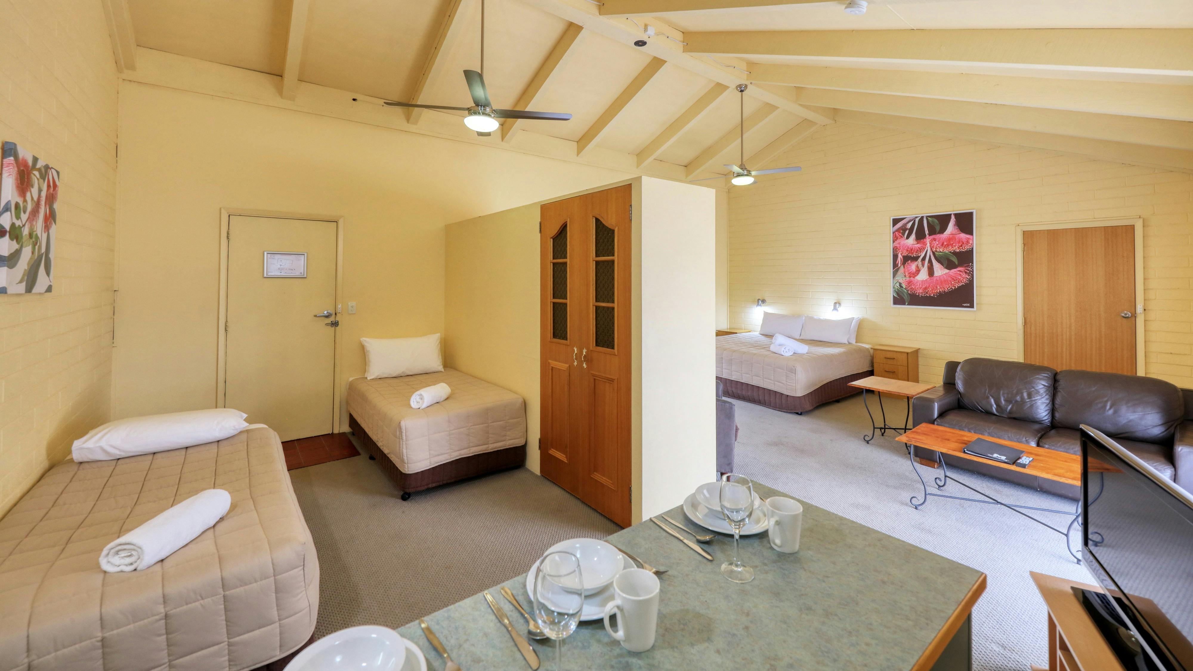 Upstairs King Suite showing kitchenette bench top with crockery, two single beds and king bed.