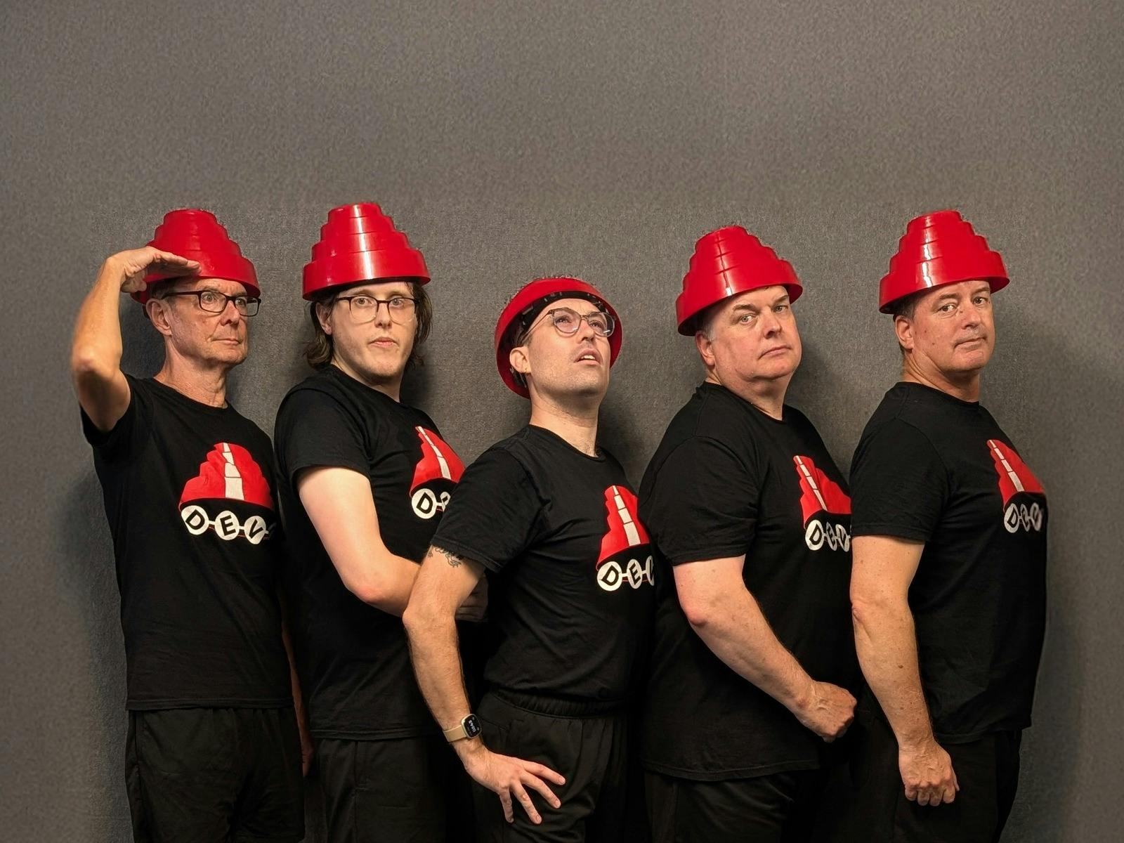 Five caucasian men of varying ages dressed in black t-shirts with red traffic cone style hats Five caucasian men of varying ages dressed in black t-shirts with red traffic cone style hats