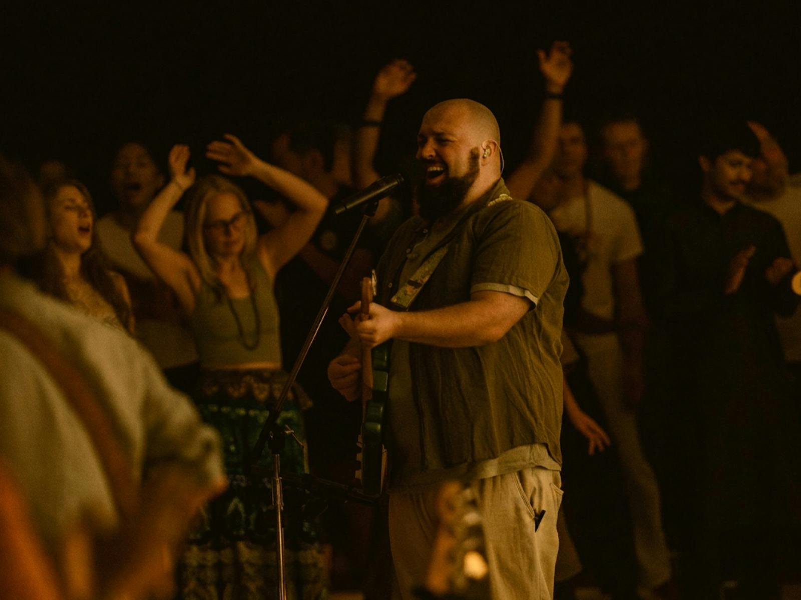 Man singing in a crowd while playing guitar