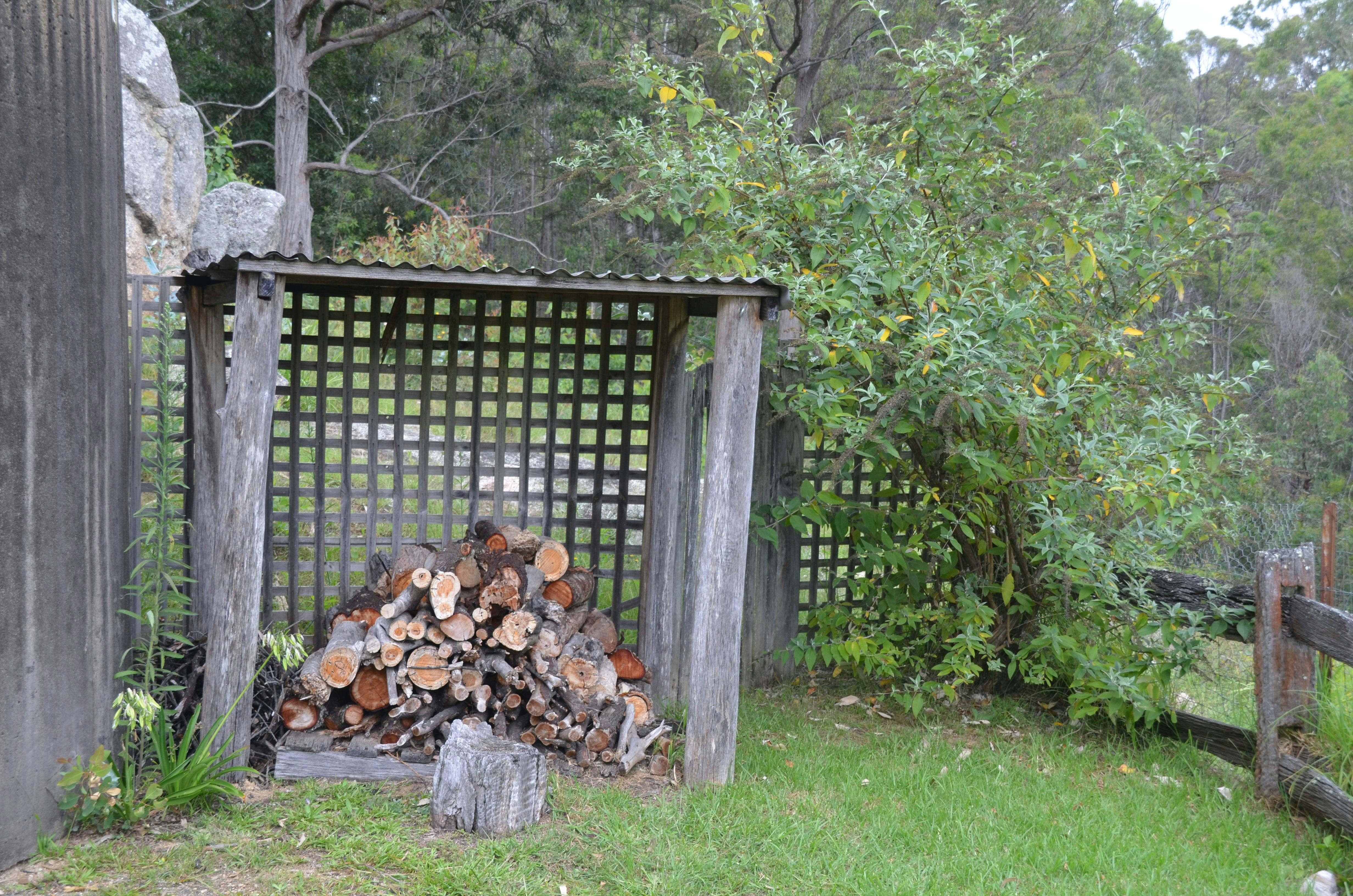 A pile of firewood within a small wood shelter