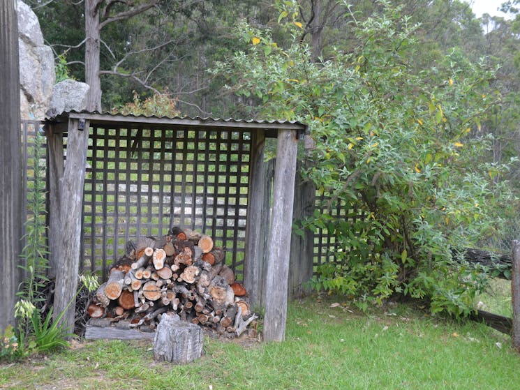 A pile of firewood within a small wood shelter