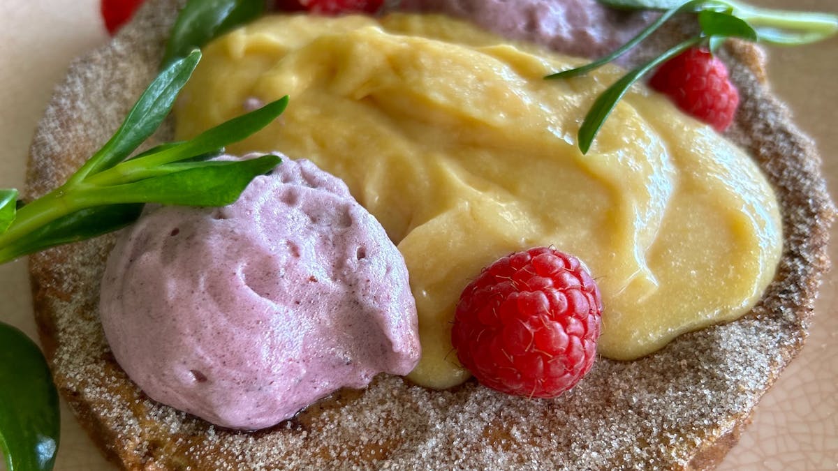 Plate of brioche French Toast with grapefruit curd and  fresh raspberries.