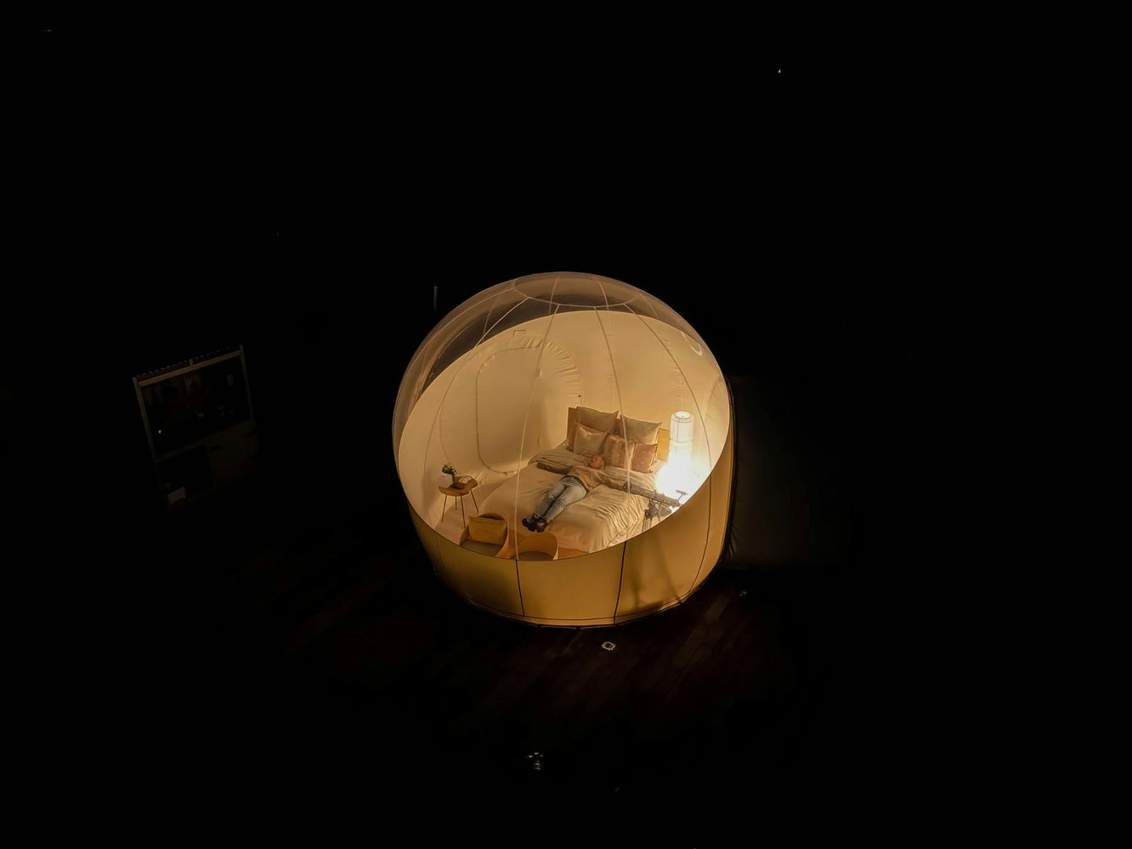 Adult lying on queen size bed watching stars in clear roof Bubbletent