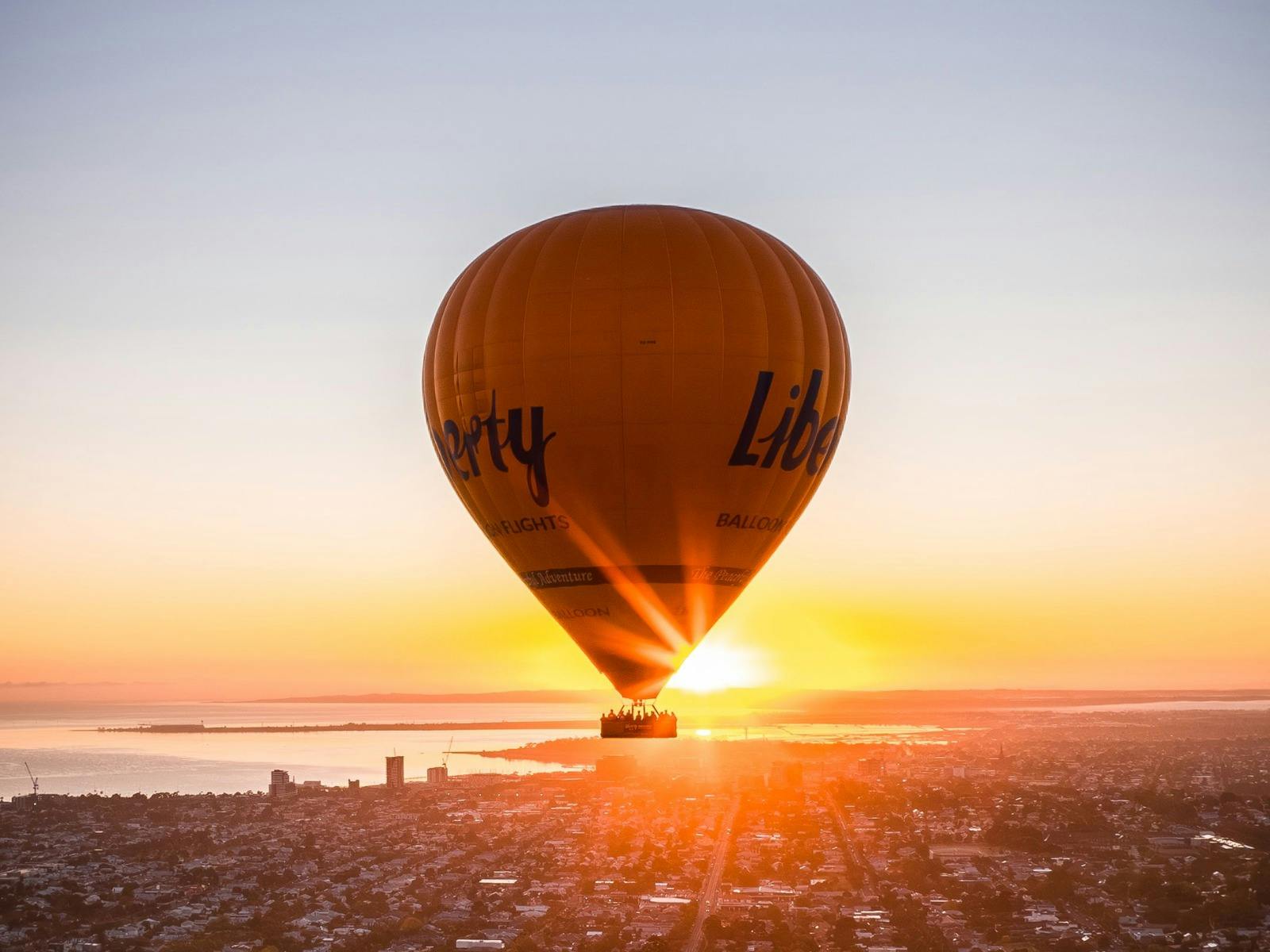 Aerial view of a balloon floating over the ocean during a breathtaking orange sunrise