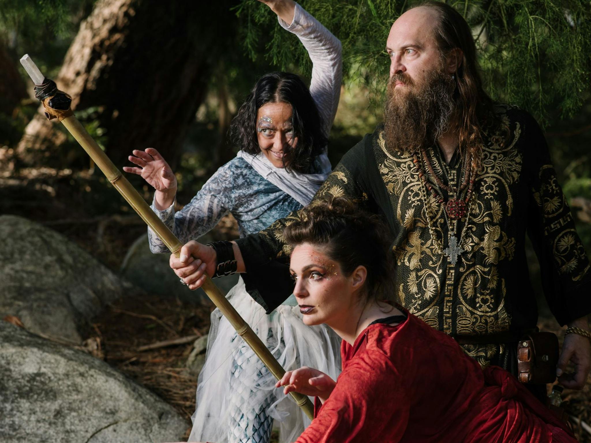 Three characters in intricate clothing, one holding a staff