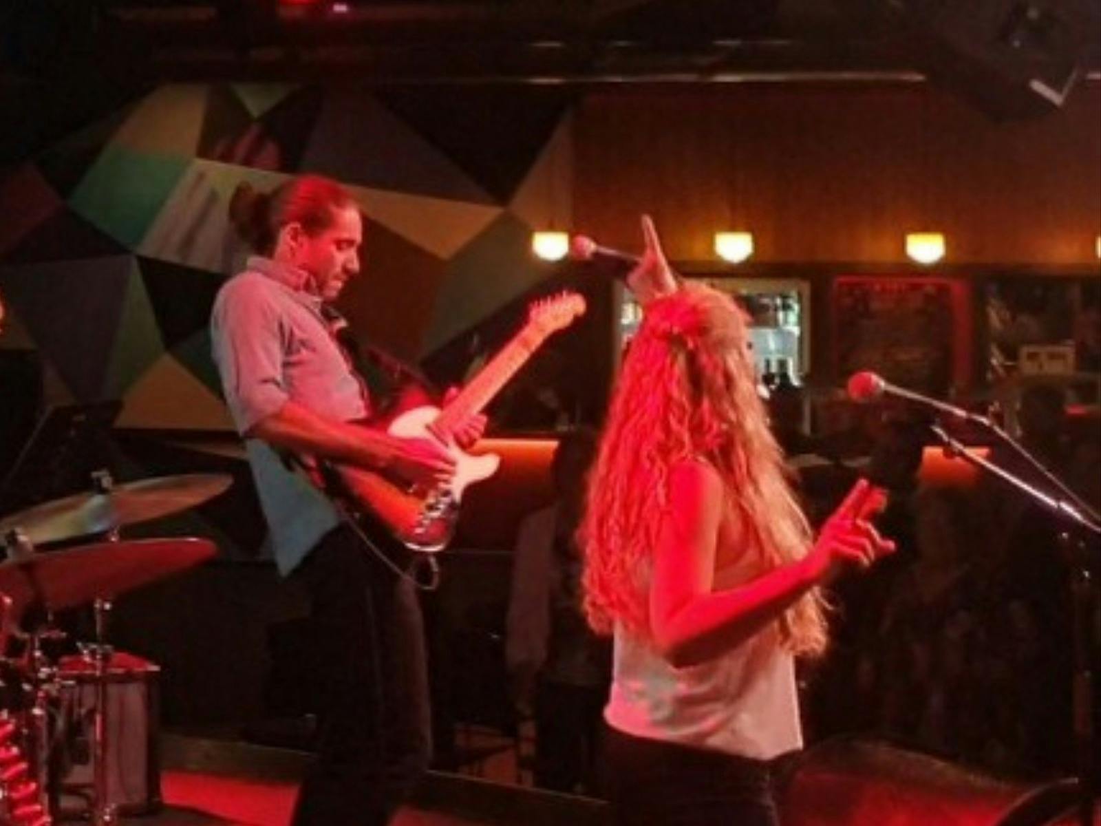 A woman and a guitarist are performing on a stage.