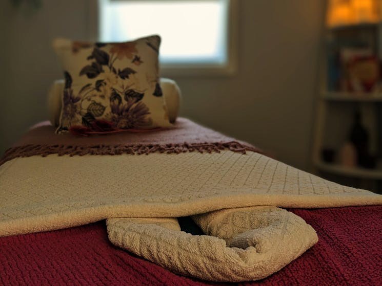 The massage table, prepared with soft towels and blankets, ready for the next client.
