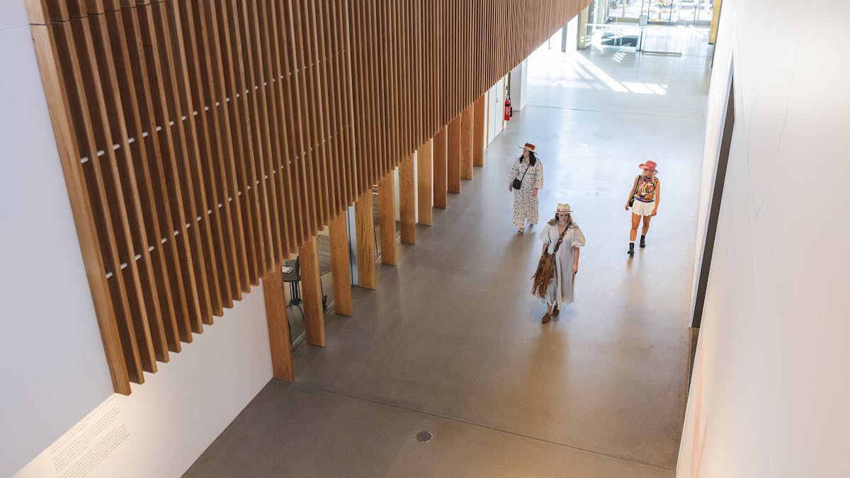 A downwards shot of three young women walking up the hallway of the art gallery