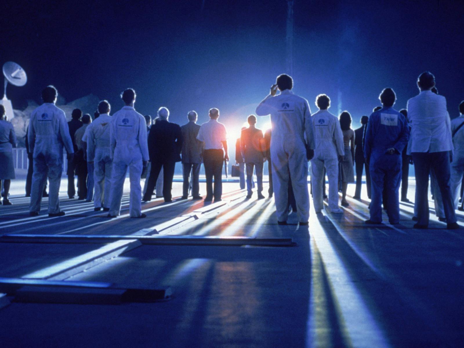 Blue glowy image with the backs of people standing in white lab coats