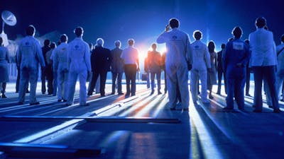 Blue glowy image with the backs of people standing in white lab coats