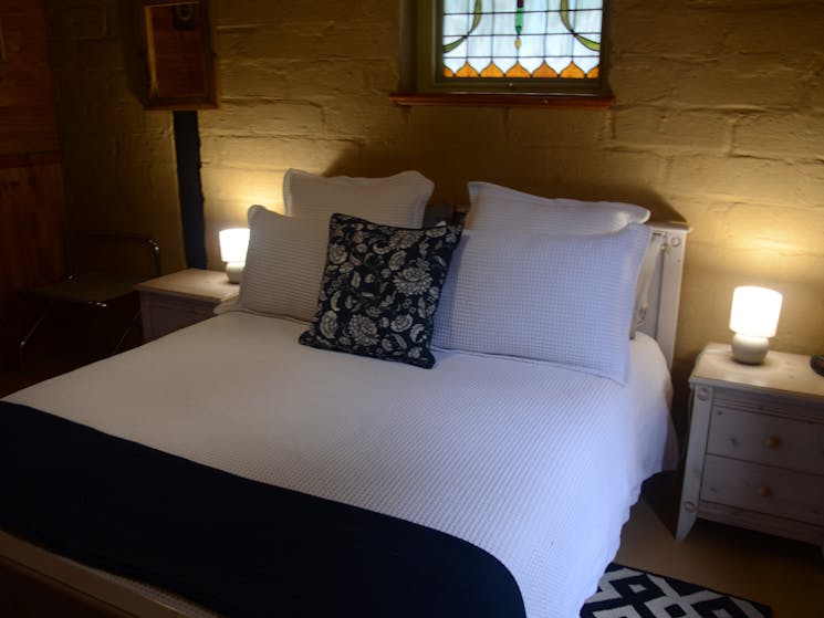 A queen bed in a rustic room in a mud-brick cottage