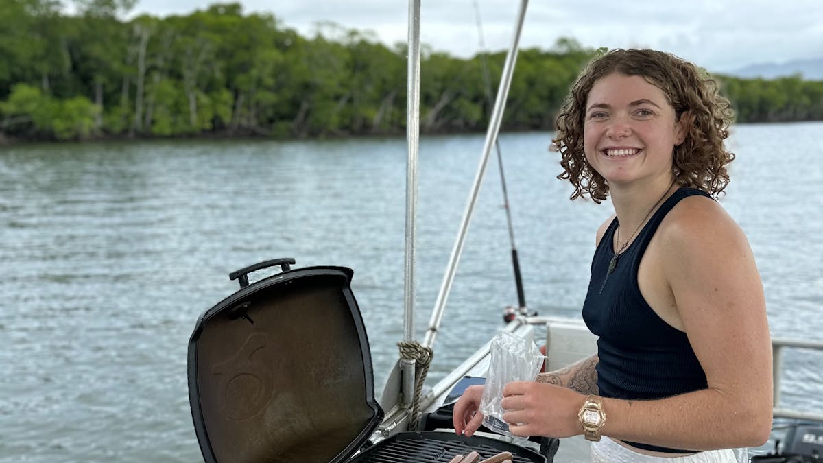 Woman BBQing some sausages on the Trinity Inlet in Tropical North Queensland Boat Hire