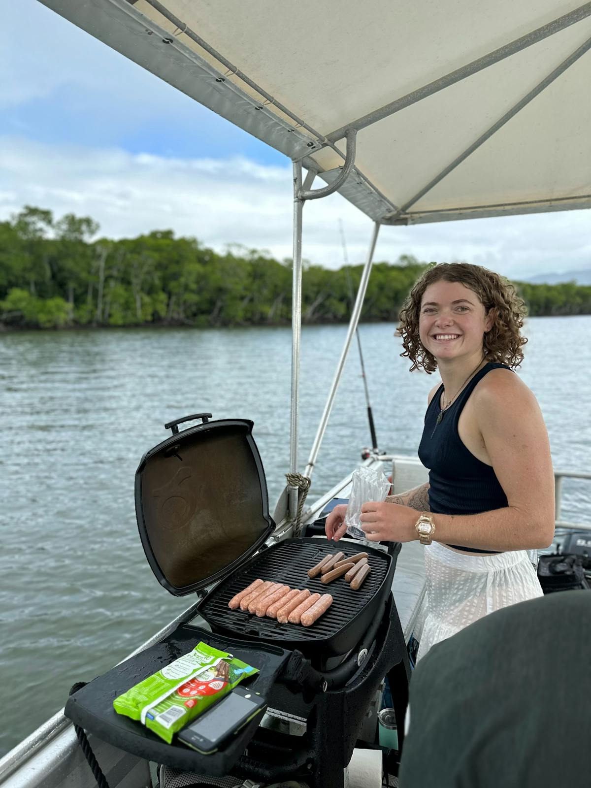 Woman BBQing some sausages on the Trinity Inlet in Tropical North Queensland Boat Hire